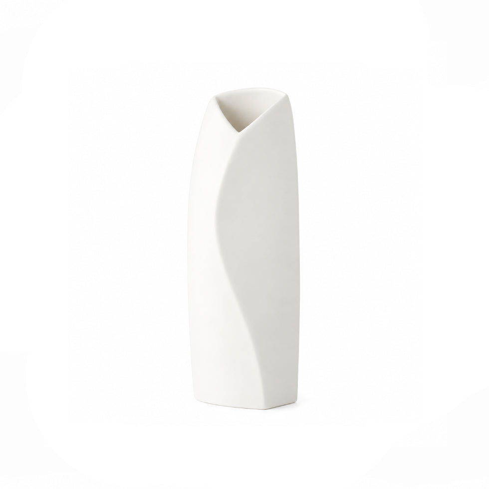 A modern, minimalist white ceramic vase with a sculptural, wavy vertical line on its front and a flared, angled opening at the top, set against a seamless white background.
