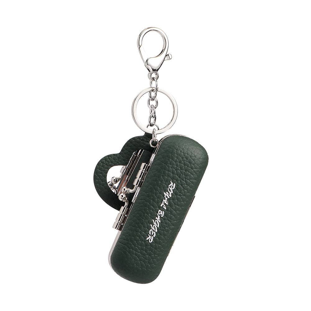 A dark green pebbled leather keychain case with a heart-shaped charm and silver-tone metal hardware, featuring the brand name 'saying right' in white script on the front.