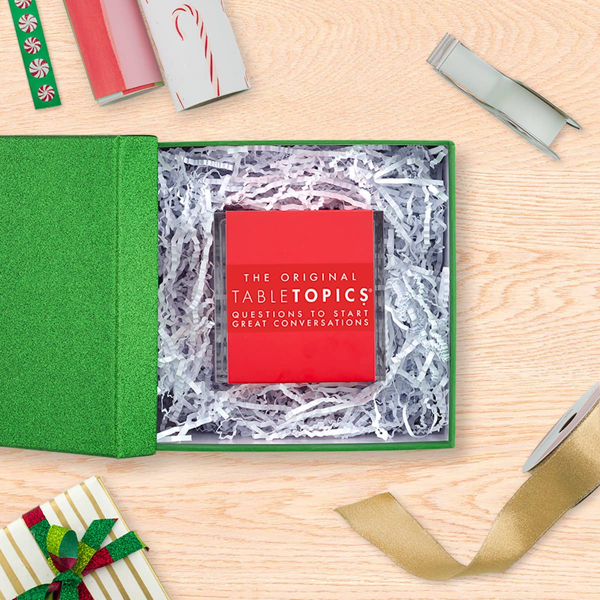 TableTopics product in a green box with decorative ribbons on a wooden surface