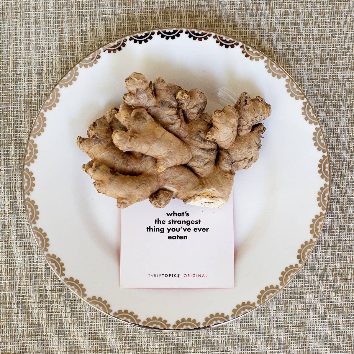 Ginger root on a decorative plate with a question card underneath
