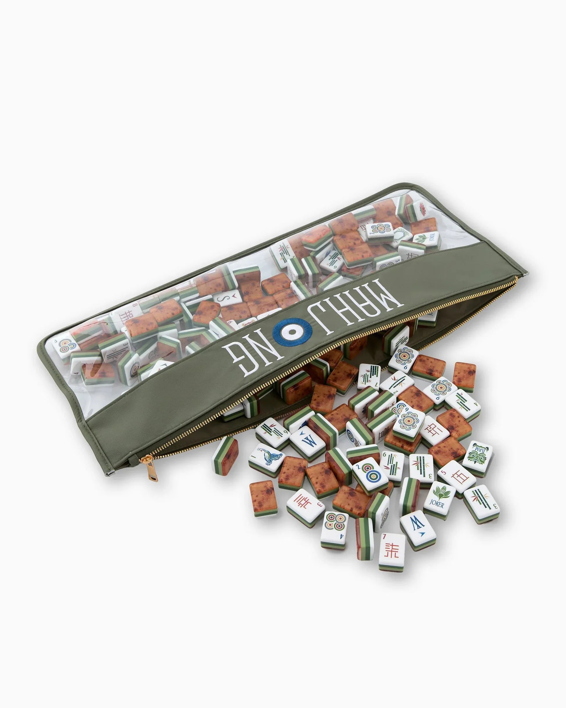 Mahjong tiles in a green clear bag with tiles spilling out on a white background