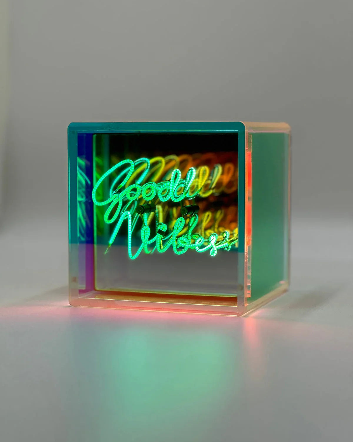 Neon sign with 'Good Vibes' text in a clear cube on a gray background