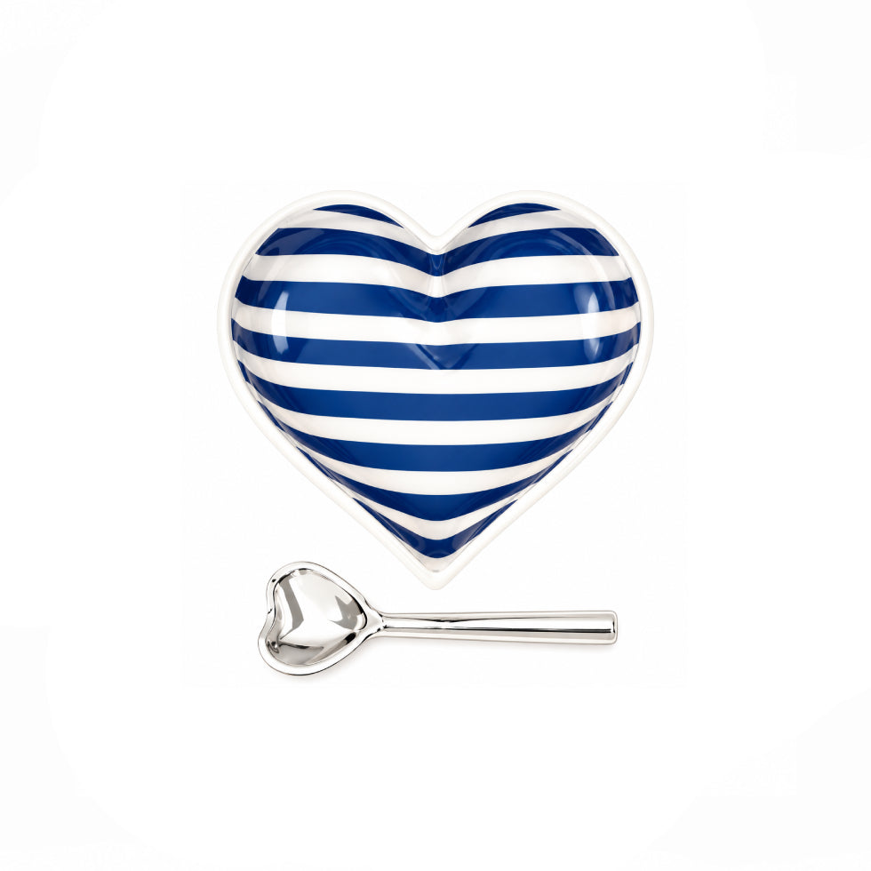 A heart-shaped ceramic dish with blue and white horizontal stripes, accompanied by a small silver metal spoon, set against a plain white background.