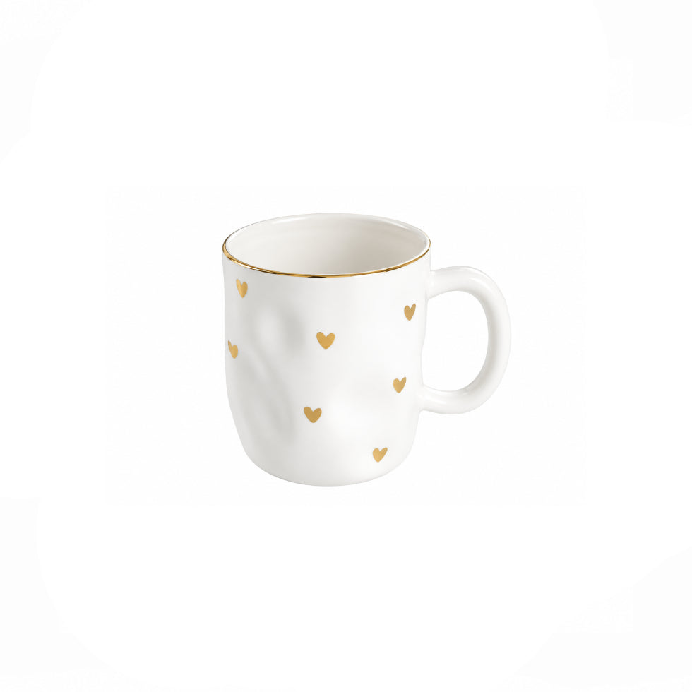 A white ceramic mug with a delicate gold rim and scattered small gold hearts, set against a plain white background.