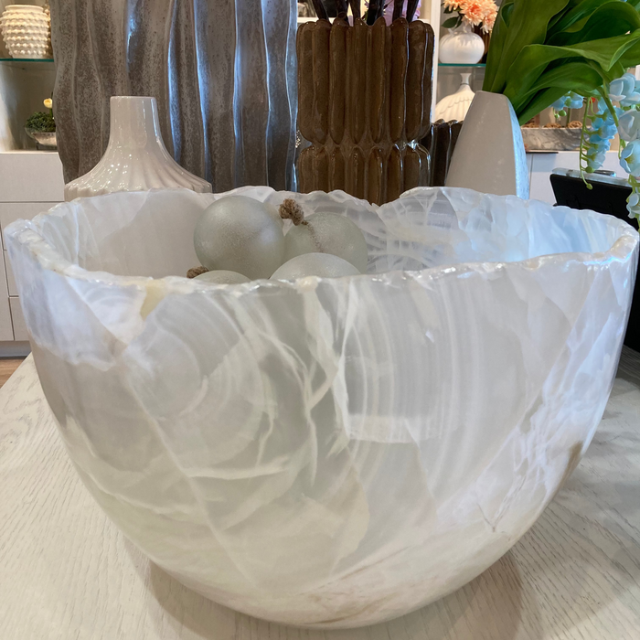 White marble bowl on a table with decorative items in the background