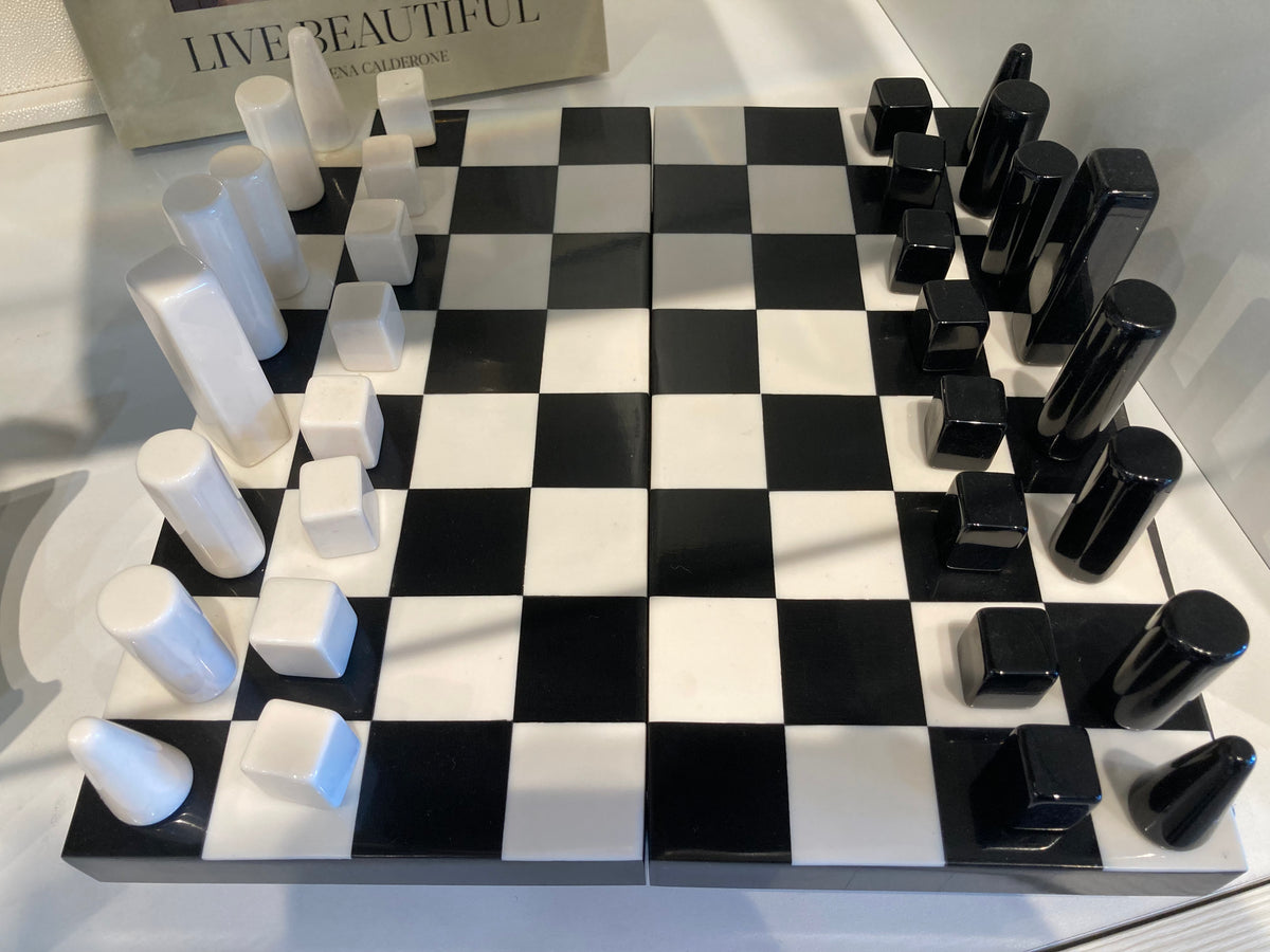Checkered chessboard with black and white pieces on a sleek surface.