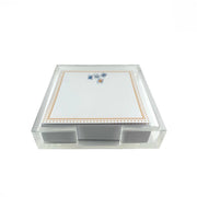 A clear acrylic notepad holder with a white notepad featuring a gold border and small playing card illustrations, set against a plain white background.