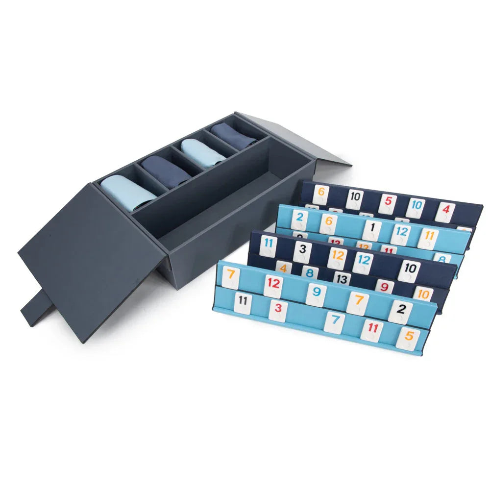Set of dice with number patterns and a gray rummikub box on a white background