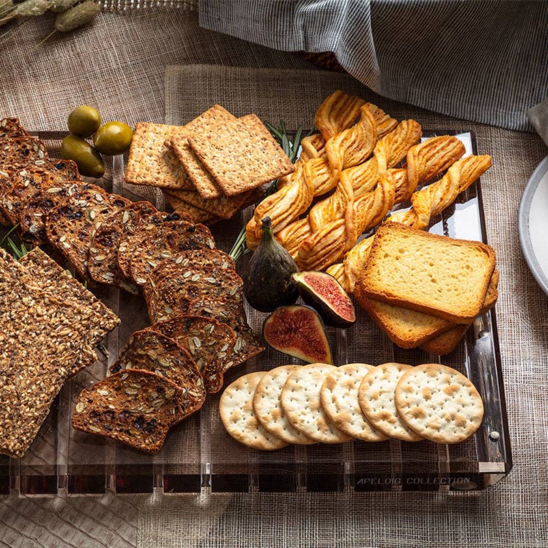 Striped smoke challah board with appetizer foods on top. 