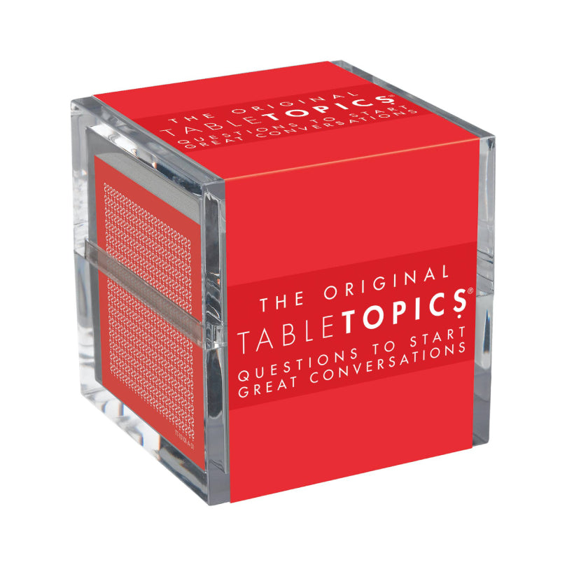 A clear acrylic cube containing a bright red book or booklet with white text reading 'The Original TableTopics Questions to Start Great Conversations.'.