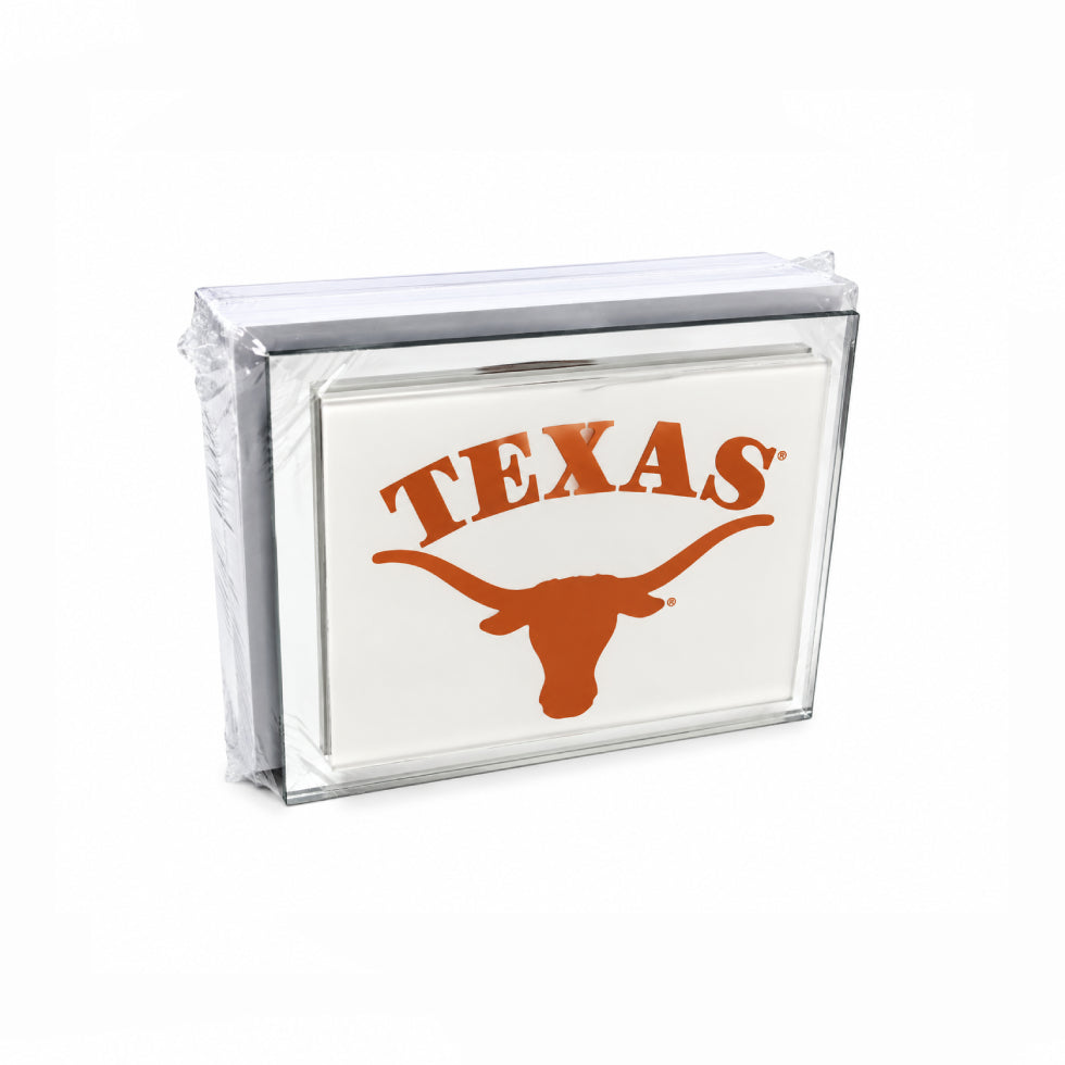 A clear acrylic-framed square sign featuring the word 'TEXAS' in orange above a large orange longhorn silhouette on a white background, shown wrapped in protective plastic on a white studio background.