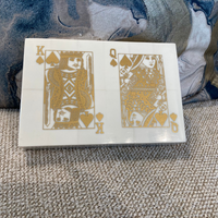 White playing card box with gold designs on a textured surface